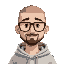 a man with short grade 0 buzz cut all over hair (almost bald) with thick black glasses, no beard, in a light gray hoody waving